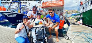Miguel en su silla de ruedas y Eva posando con la tripulación del barco